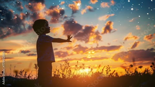 A silhouette of a little child reaching out to grab stars, Expresses the ambition, The joy of a small child with dreams. Kid having fun at sunset.