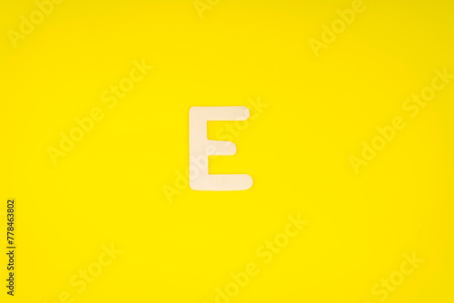 Letter E in wood on yellow background