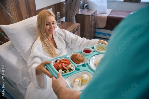 Pleased inpatient being served lunch in private clinic ward