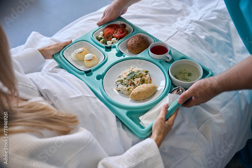 Nursing assistant serving meal to recumbent patient © Viacheslav Yakobchuk