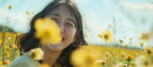 A girl, youthfully dressed, is standing amidst a blooming field of vibrant yellow flowers under the sun's warm glow photo