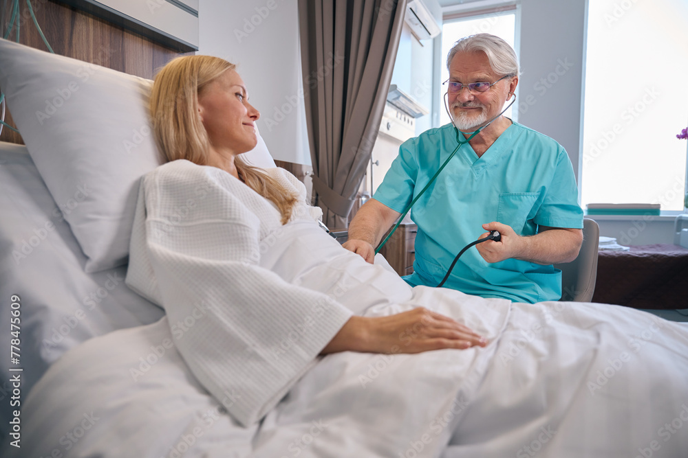 Doctor conducting physical examination of female patient during ward round Doctor conducting physical examination of female patient during ward round