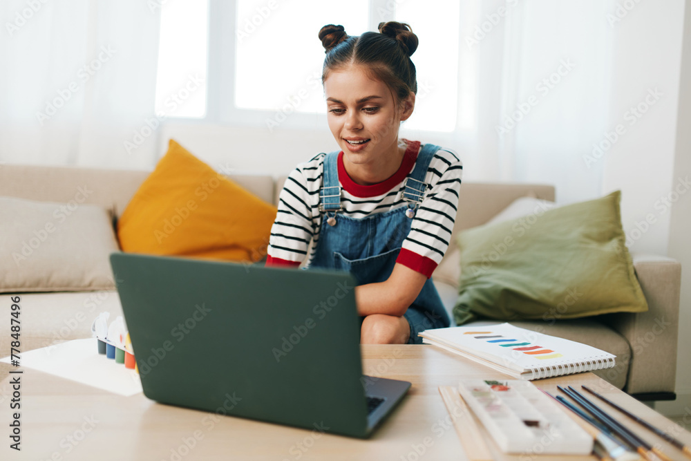 Creative Teenage Artist at Home: Happy Girl Painting a Cute Portrait on Laptop, Surrounded by Art Supplies and Inspirational Artwork. Creative Teenage Artist at Home: Happy Girl Painting a Cute Portrait on Laptop, Surrounded by Art Supplies and Inspirational Artwork.