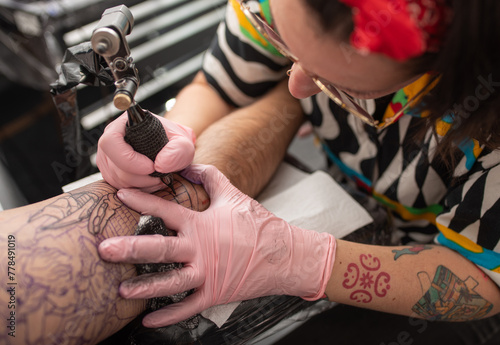 Tattoo artist woman performing a tattoo on an arm