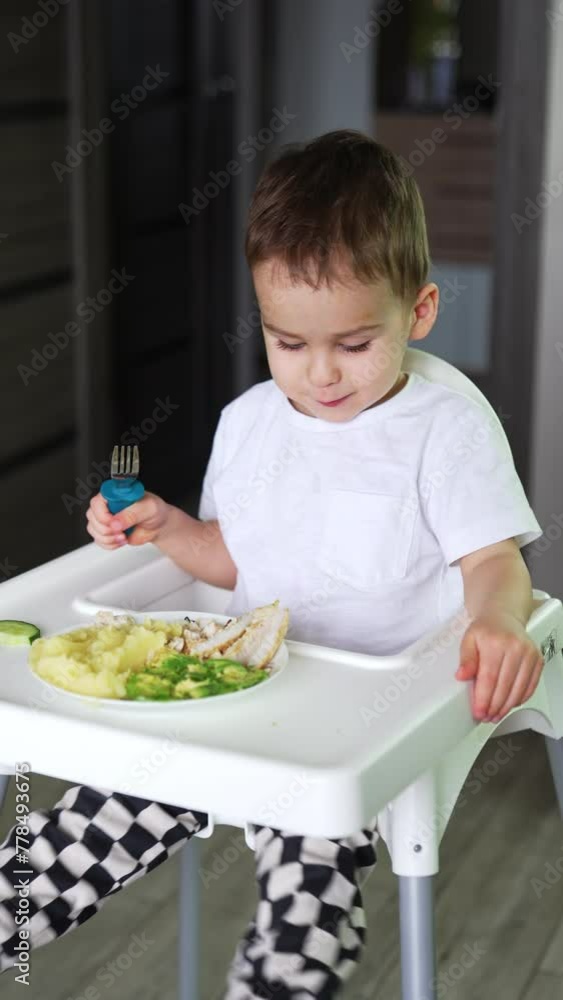 Cheerful small boy eating at the table. Infant little kid having breakfast. Vertical video. Cheerful small boy eating at the table. Infant little kid having breakfast. Vertical video.