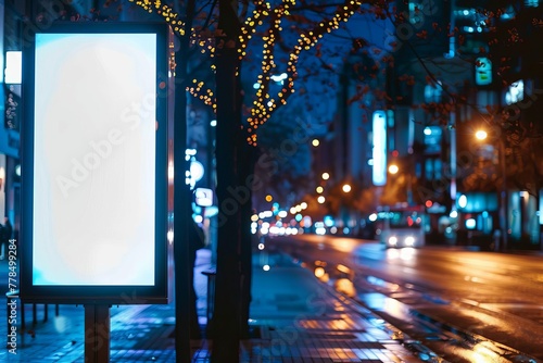 Empty white vertical digital billboard at night in city with blurred urban background, mockup