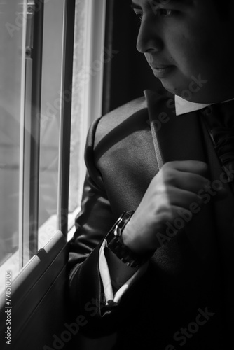 Man by a window and his right arm up showing his watch