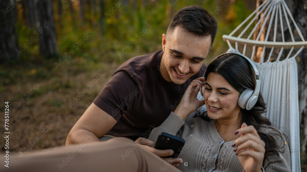 Man and woman young adult couple in nature listen music headphones Man and woman young adult couple in nature listen music headphones