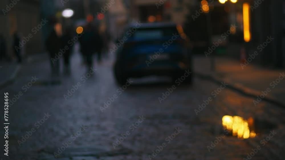 Car with headlights driving on cobblestone street at night Car with headlights driving on cobblestone street at night