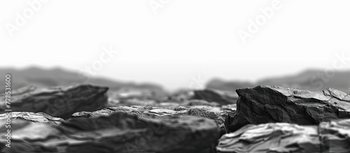 A monochrome photo of a rocky outcrop with mountains in the background, showcasing a natural landscape under a wind wavefilled sky