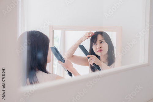 ヘアアイロンを使って髪をセットする若い女性