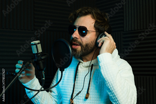 Male singer with sunglasses during a recording session in a studio