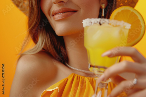 Cropped view of woman drinking margarita cocktail on orange