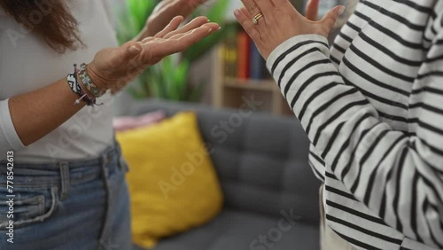 Mother and daughter conversing with hand gestures in a cozy living room setting expressing family dynamics and bonding photo