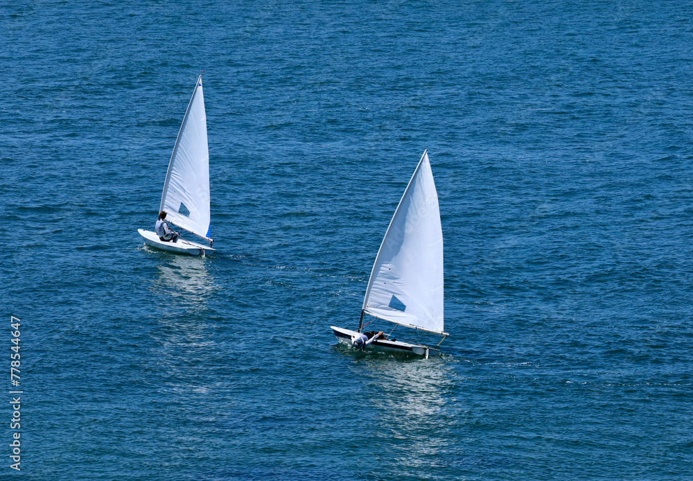 two small sailboats tacking across the bay