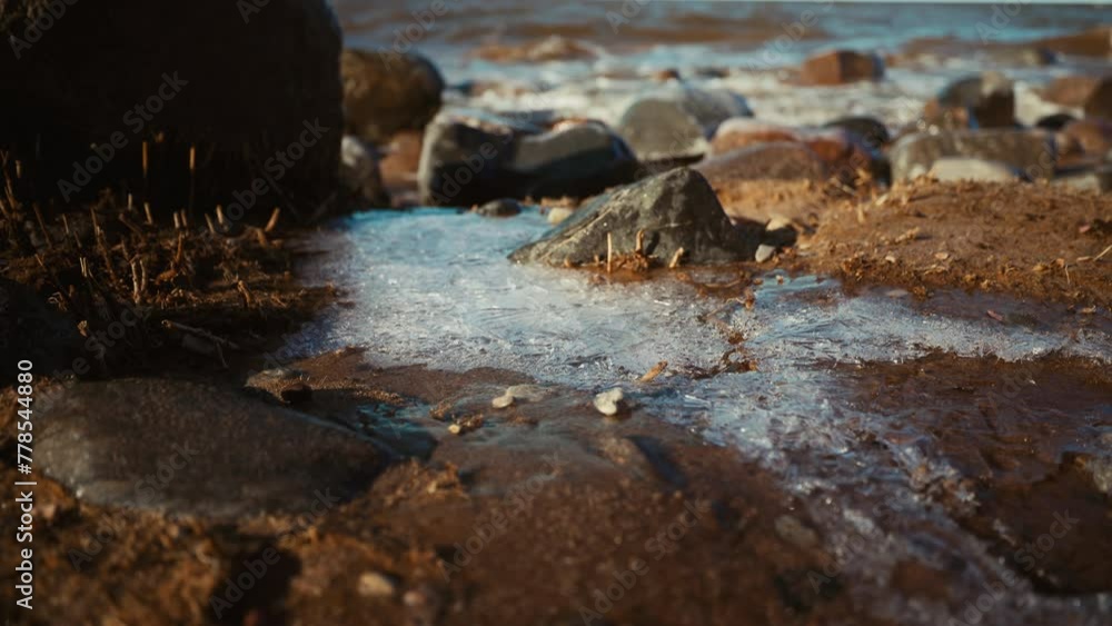 Close up of rocky beach with icy rocks, water, and natural landscape Close up of rocky beach with icy rocks, water, and natural landscape