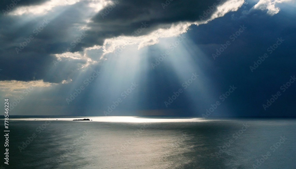 Dramatic interplay of light and shadow: sunbeams pierce clouds over a vast ocean