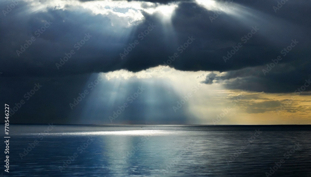 Ocean illuminated by sunlight breaking through dark clouds, creating a dramatic seascape