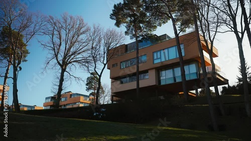 Retreat in spring: The building's fa ade, adorned with many windows and balconies, is framed by blooming trees, setting the scene for a tranquil vacation. photo