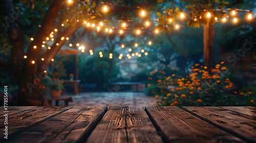 Empty wood table for product display with decorative outdoor string lights hanging on tree at night time.