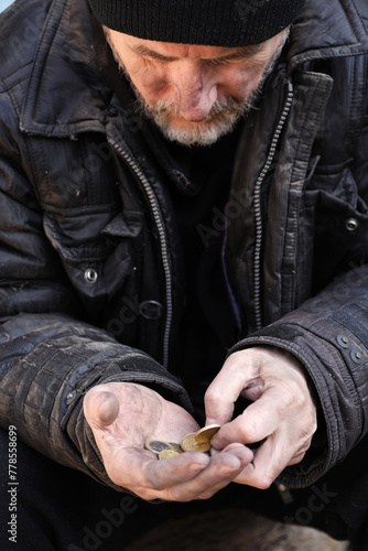 Poor homeless senior man holding coins outdoors