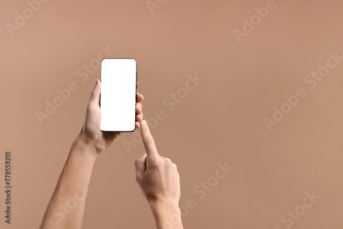 Man using smartphone with blank screen on beige background, closeup. Mockup for design