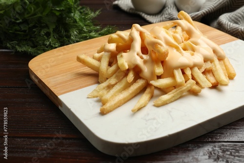 Foto Delicious french fries with cheese sauce on wooden table, closeup
