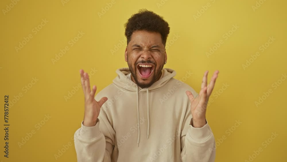 Excited african american man in a hoodie going mad with joy, celebrating a crazy success win with arms flung wide! winner vibes on a yellow isolated background. Excited african american man in a hoodie going mad with joy, celebrating a crazy success win with arms flung wide! winner vibes on a yellow isolated background.