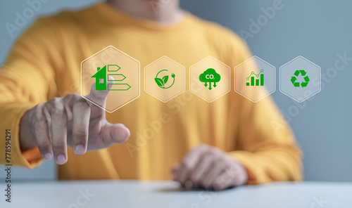 Energy efficiency concept. Businessman touching energy efficiency rating icon on virtual screen for energy efficient house building rate label audit.