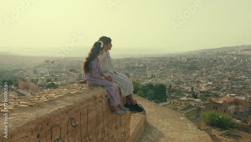 Kids Overlooking Old City of Fes in Morocco while sitting on a wall photo