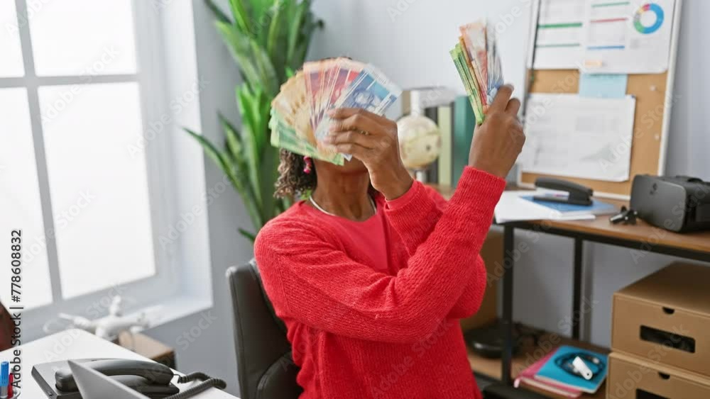 A joyful african woman in an office holding south african rand currency ...