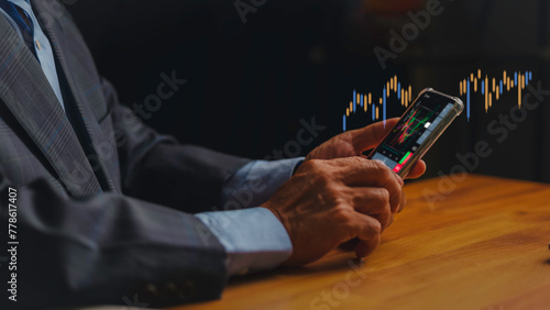 Businessmen are using smartphones to analyze stock charts and investing in funds, stock market, trading and observing the ups and downs of the stock board.