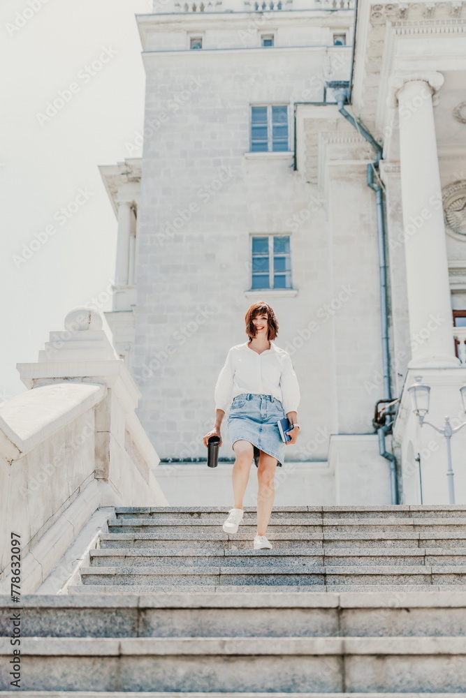 Woman staircase city. A business woman in a white shirt and denim skirt walks down the steps of an ancient building in the city