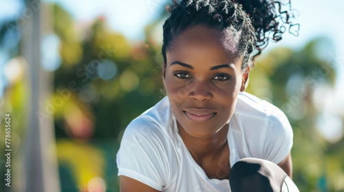 Black afro american woman in her 40s wearing white shirt top exercising outdoor looking directly at the camera