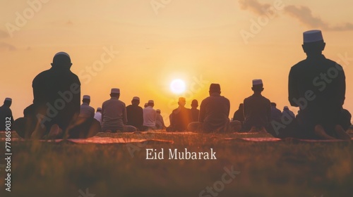  a vast field. Rows of people kneel in unison, silhouetted against a breathtaking sunrise. The text Eid Mubarak is written in a bold, Arabic font across the top of the scene.