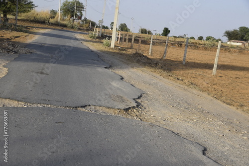 Bad road, cracked asphalt with potholes and big holes. Potholes on the road with stones on the asphalt. The asphalt surface is destroyed on the road. Bad condition of the road