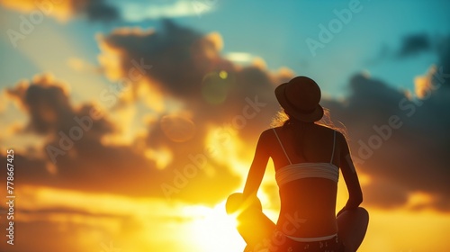 Silhouette of woman with bikini swimming wear sit and enjoy view of sunset with clouds and yellow orange sky
