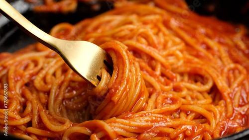 Stirring spaghetti with tomato sauce