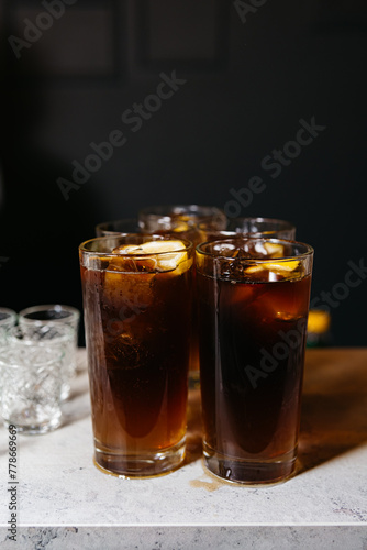 Iced Cola Drinks in Tall Glasses. Several glasses of iced cola on a counter, showcasing a refreshing drink option for social gatherings or a hot day.