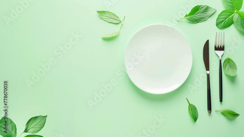 An elegant dining setup with white empty plate, leaves, knife and fork, ideal for food themes