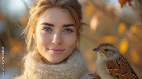 a close up of a person with a bird on her shoulder and a tree in the background with leaves in the foreground. © Mikus