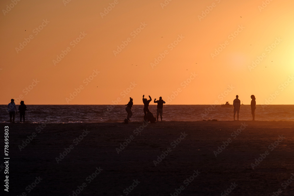 Playa de Tarifa, Cádiz, atardecer en la playa, alegria y fiesta, personas disfrutando de los últimos rayos de sol en la arena de la palya, luz dorada