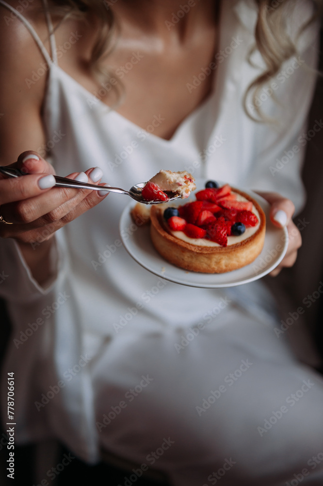 The image shows a woman eating a bowl of berries in an indoor setting 6979.