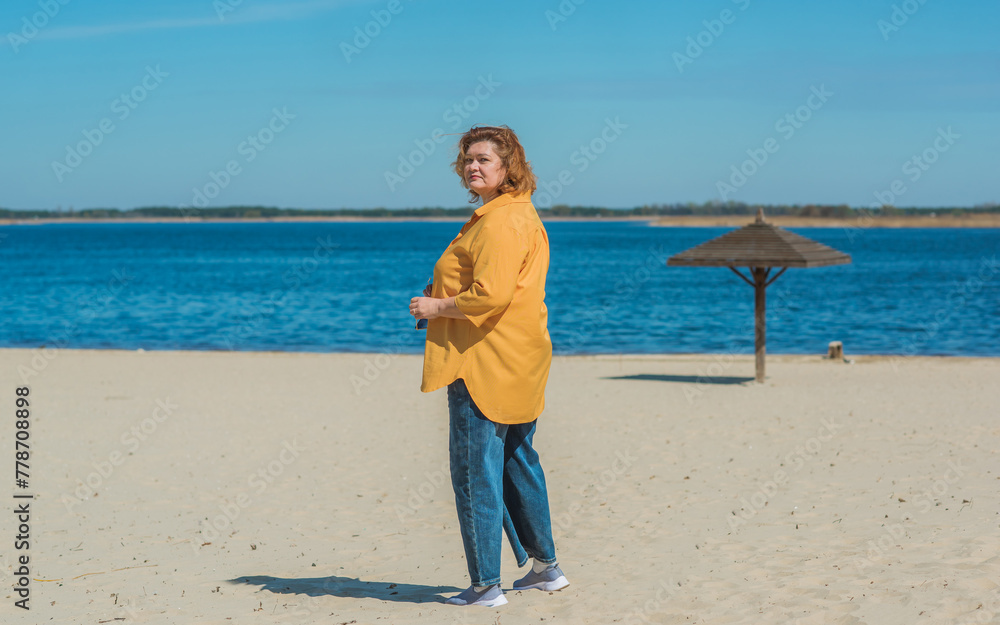 Vacation mood. Plus size happy mature lady wear yellow shirt and blue pants at beach , spring - summer clothes collection Vacation mood. Plus size happy mature lady wear yellow shirt and blue pants at beach , spring - summer clothes collection