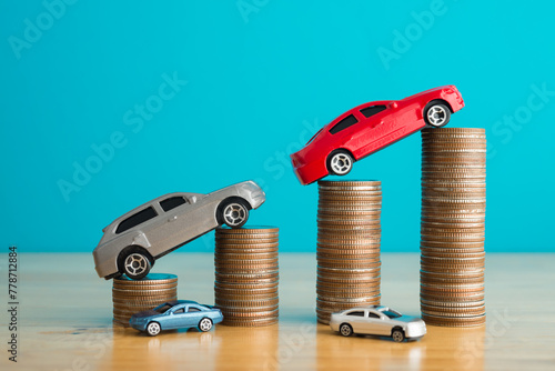Car model on stacked coins as growth chart graph on wooden table with blue background. Business, financial and economy concept. Car price increase in inflation, money savings for new or used car.
