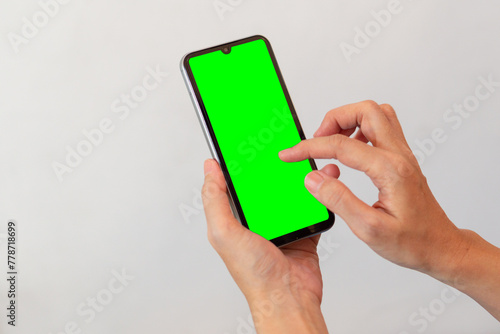 women hand holding smart mobile phone with blank green screen on isolated white background