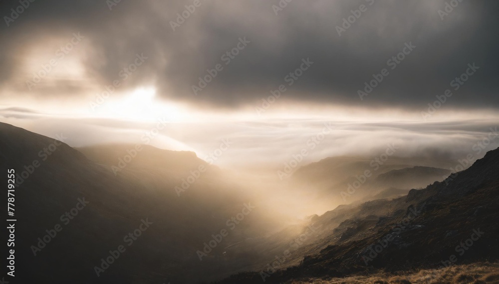 epic gloomy landscape close up moonlight breaks through heavy clouds and illuminates sections of the gloomy valley dissipating in the fog cinematic