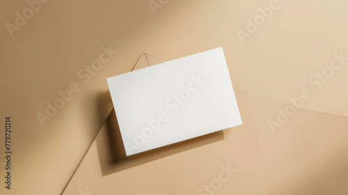 Blank white card propped up against a beige wall with shadow detail.