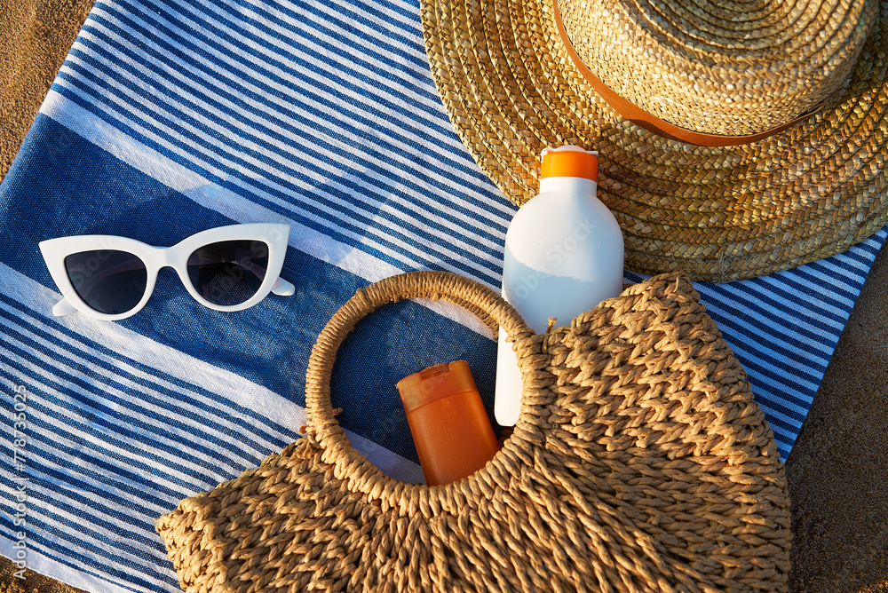 custom made wallpaper toronto digitalBeach essentials laid on striped towel at golden hour. Woven straw, oversized white sunglasses, sun cream bottles in natural tote bag imply summertime skin care. Holiday scene by sea shore.