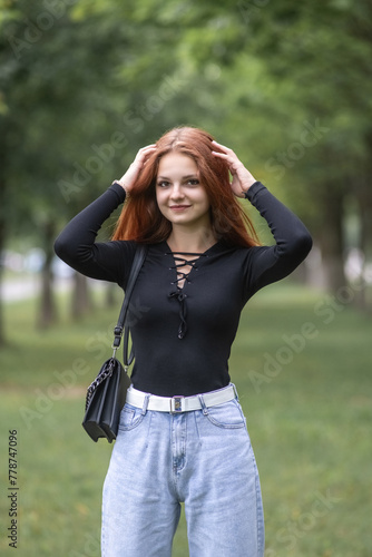 Portrait of a young beautiful red-haired girl in a summer park.